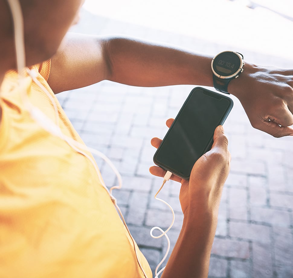 Eine Person hält ihr Smartphone neben die Uhr und vergleicht was auf den Bildschirmen zu sehen ist.