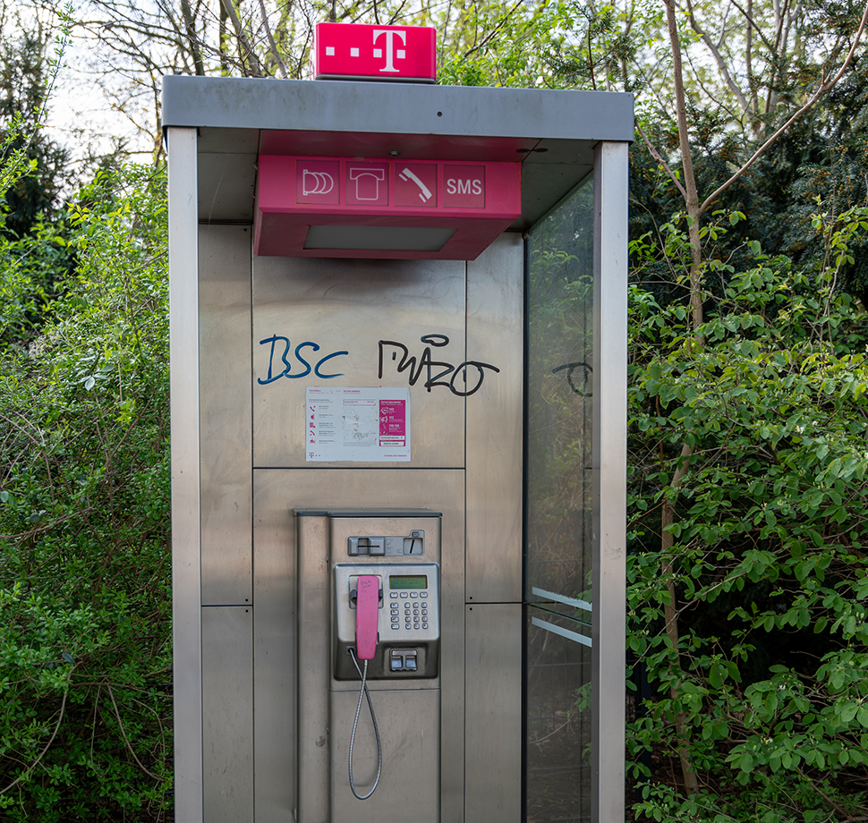 Eine Telefonzelle von der Telekom die etwas heruntergekommen aussieht.