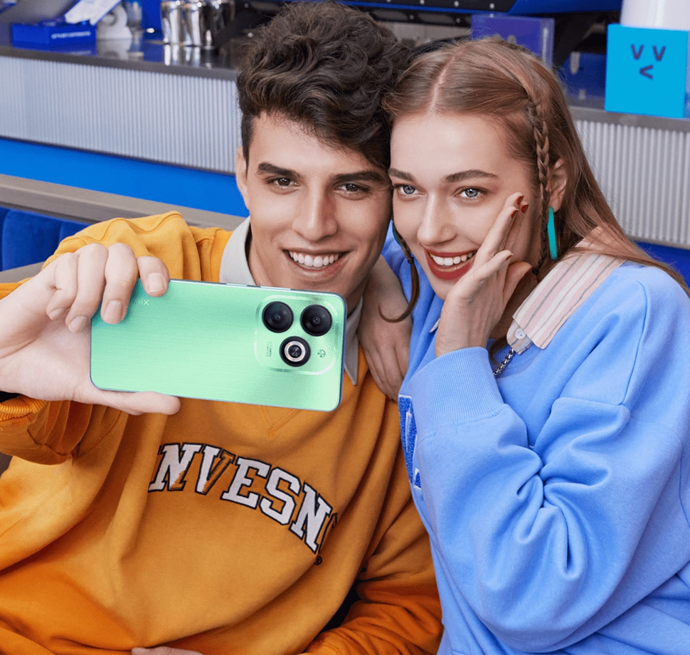 Zwei Personen machen ein Selfie mit einem türkisem Smartphone.